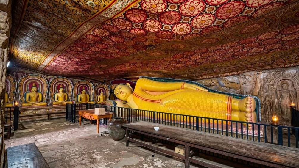 Eine große liegende Buddha-Statue in einem Tempel mit aufwendiger Decke und kleineren Buddha-Statuen im Hintergrund. 3