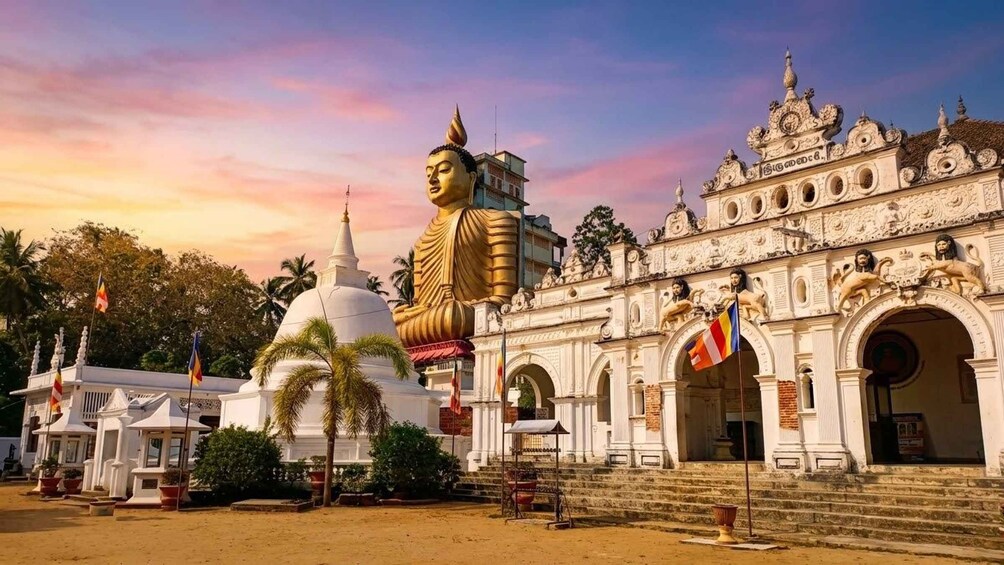 Eine große goldene Buddha-Statue, weiße Tempelgebäude und verzierte weiße Häuser mit Fahnen. 1