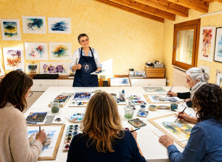 An art class with students painting and an instructor demonstrating techniques. 5