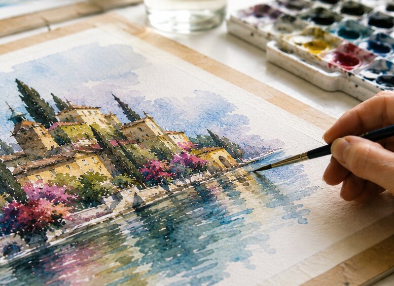 A hand painting a watercolor landscape of a castle with trees and water. 4