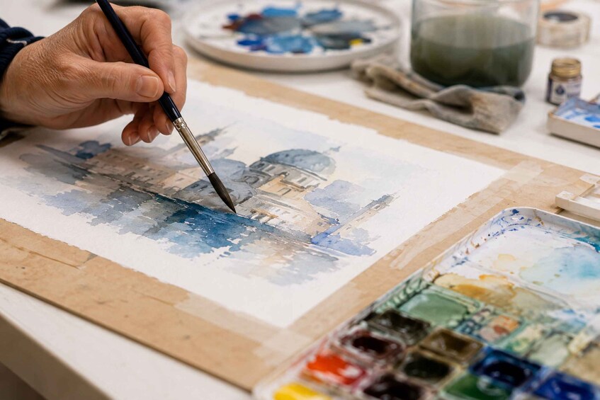 A person painting a landscape with a watercolour palette. 1