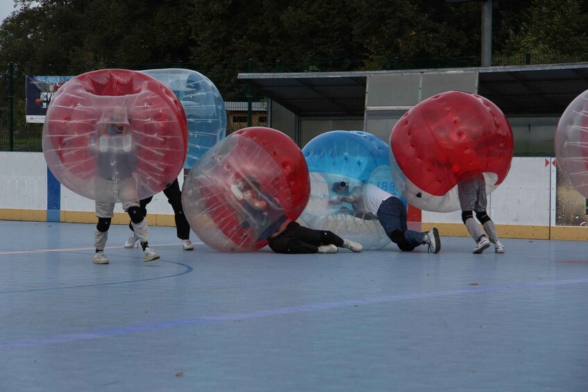 Personas dentro de esferas inflables transparentes en una cancha deportiva. 2
