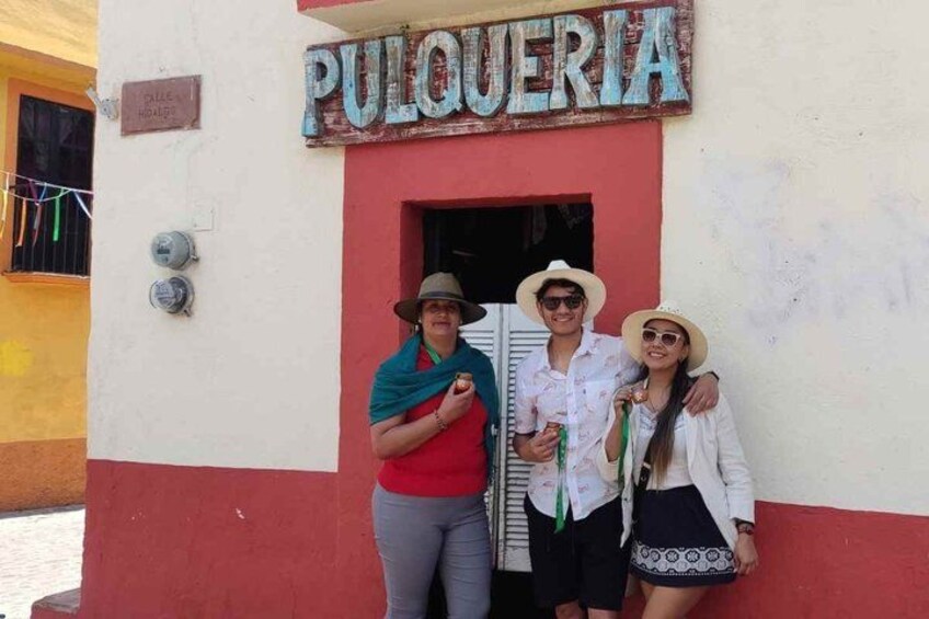 A building with a sign that reads 'PULQUERIA' and a group of people standing in front of it. 5