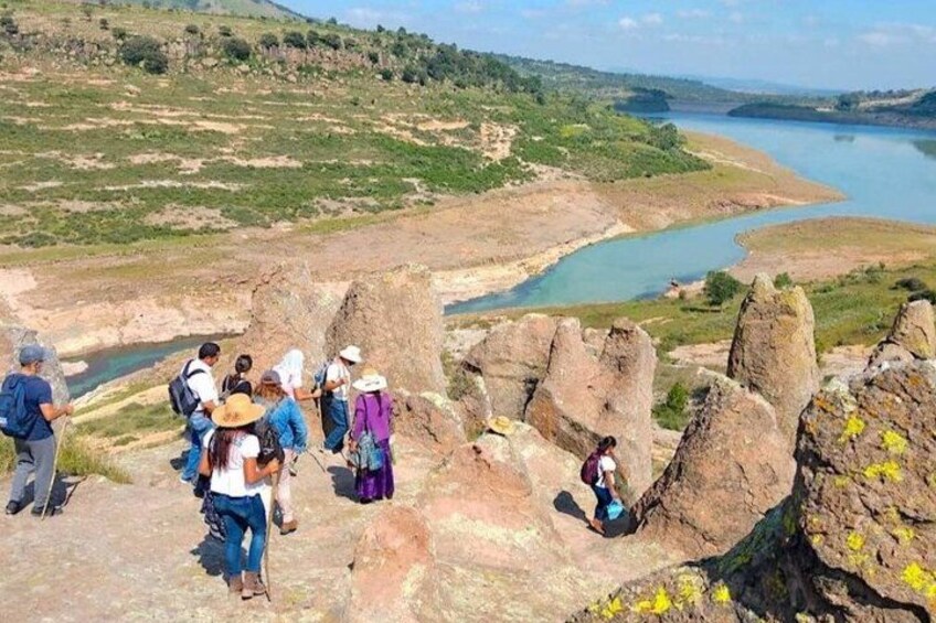 A group of hikers on a rocky terrain overlooking a river and a distant landscape. 2
