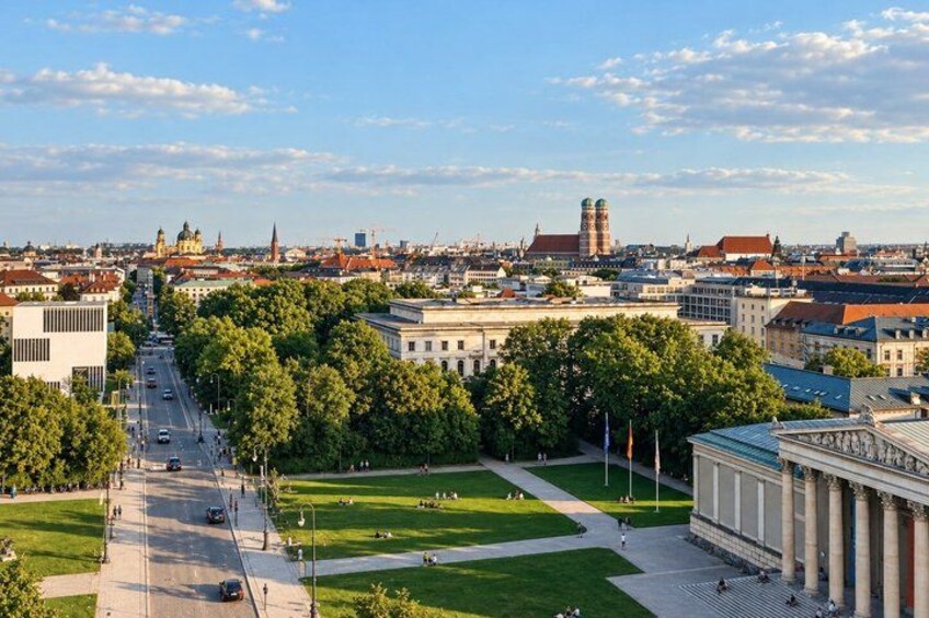 A cityscape with a prominent building with columns, a large green park, and a historic tower in the background. 5
