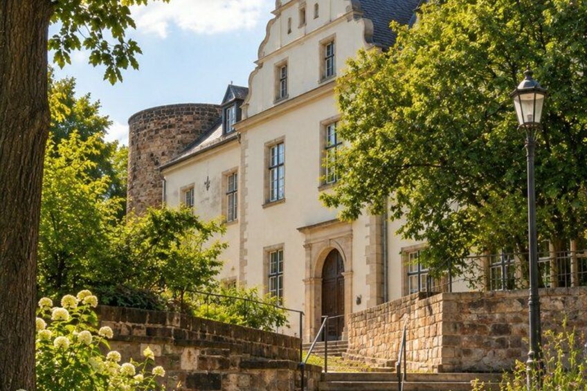 A historic building with a stone tower, surrounded by lush greenery and a stone wall. 3