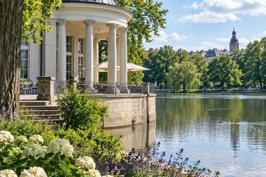 A classical building with columns, a lake, and a distant tower. 2
