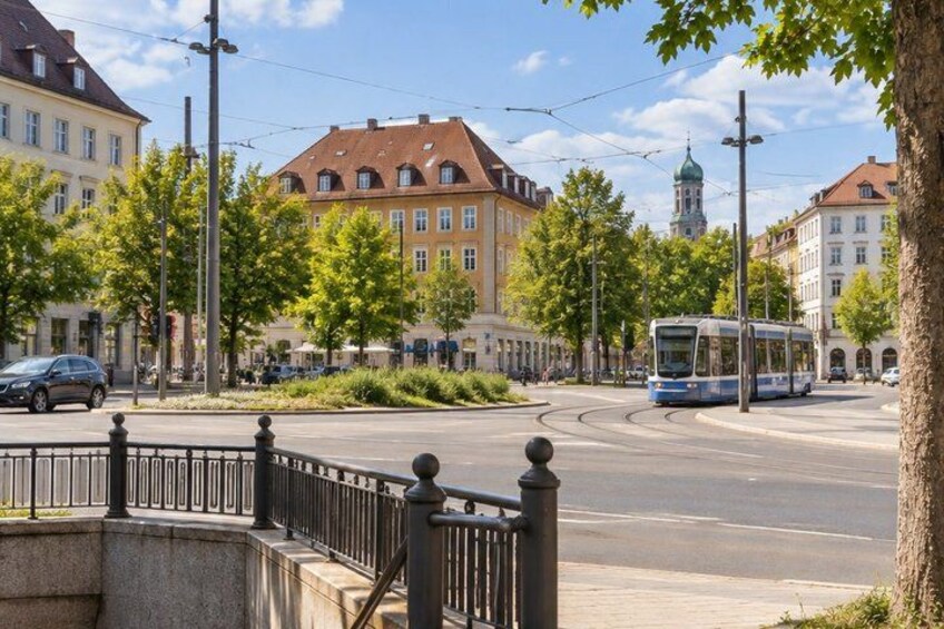 A tram on a curved track, a roundabout, and buildings with red roofs. 2