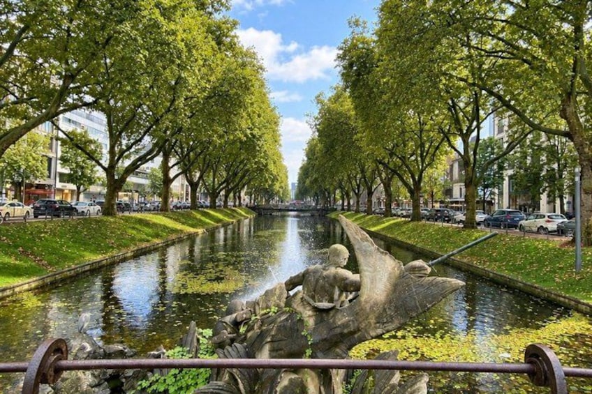 A canal lined with trees and a statue. 4