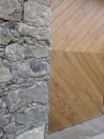 A stone wall and a wooden herringbone floor. 1