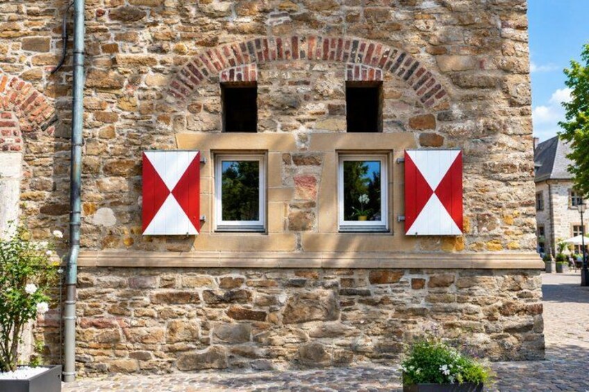 A stone building with arched windows and red and white diamond-shaped decorations. 4
