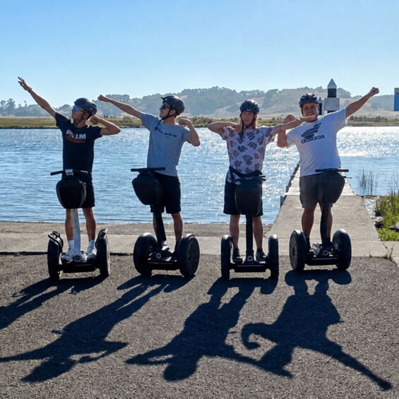 Four people on segways by a lake with a pier. 3