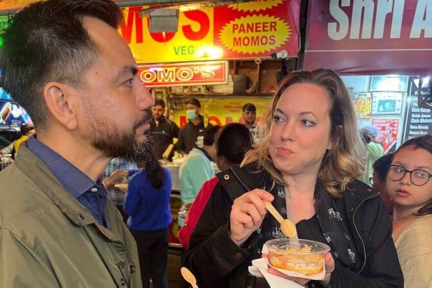Un vendeur de nourriture de rue avec une pancarte indiquant « PANEER MOMS » et une personne en train de manger. 1