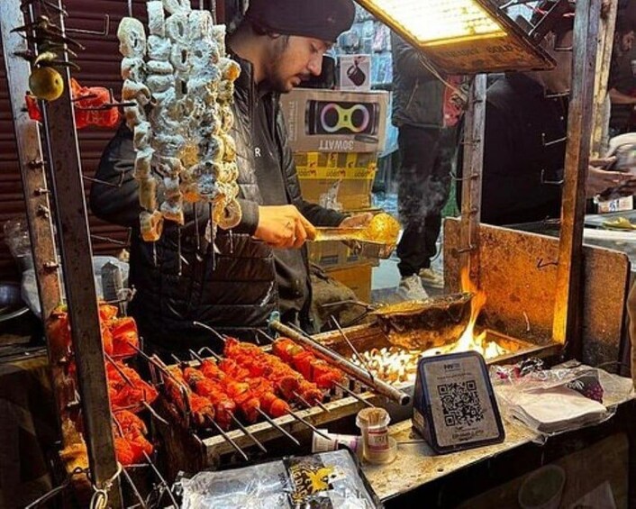 Un venditore di cibo di strada cucina all'aperto, con un codice QR e un terminale di pagamento. 5