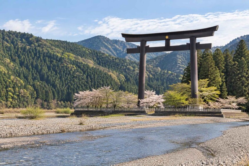 A torii gate in a natural setting with a river and mountains in the background. 2