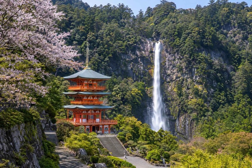A traditional Japanese pagoda with a waterfall in the background. 4
