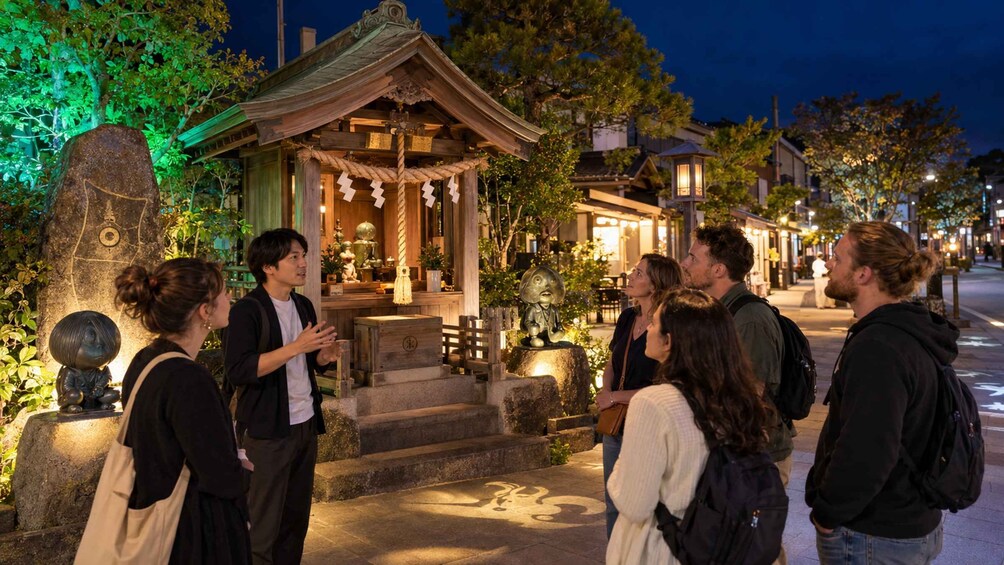 Un grupo de personas de pie frente a un edificio japonés tradicional por la noche. 5