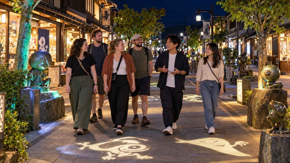 Un grupo de personas caminando por una calle iluminada de noche, con farolas decorativas y esculturas. 1