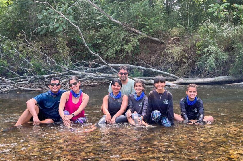 A group of people in a river surrounded by trees. 2