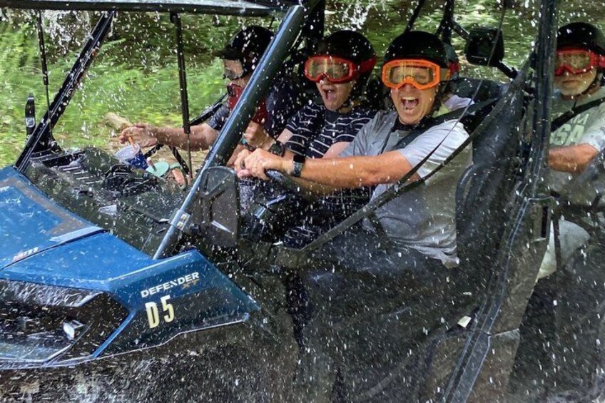 A group of people in a vehicle with water splashing around them. 1