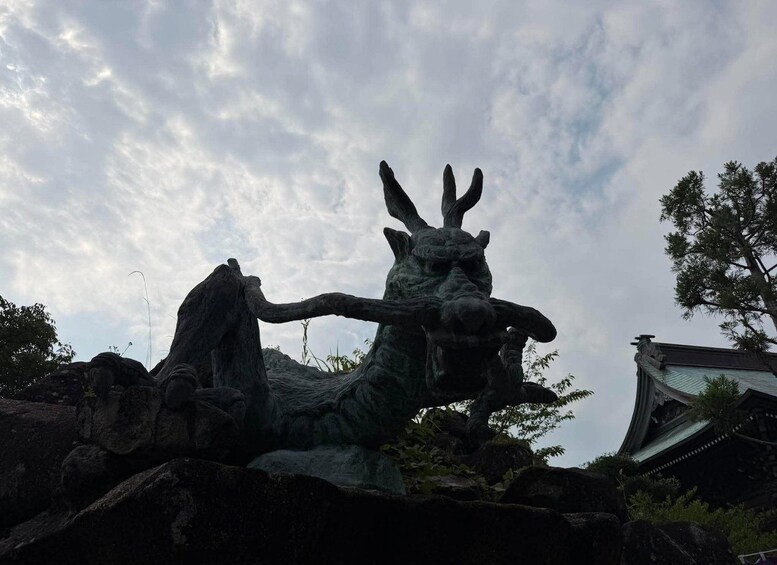 A large, dark-colored statue of a mythical creature with horns and a long neck, set against a cloudy sky. 5