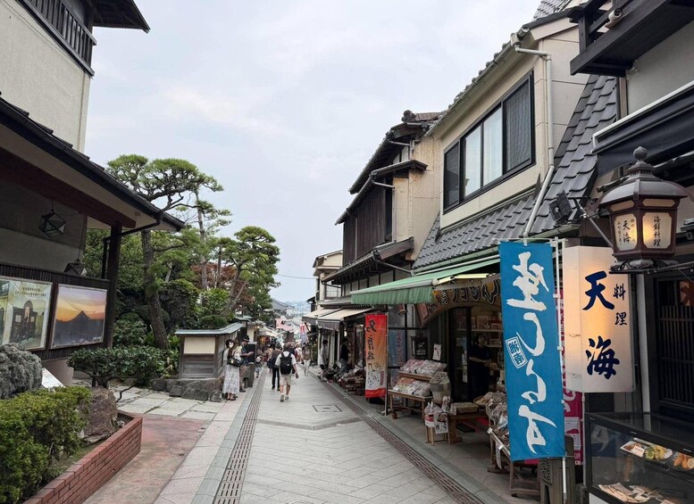 A narrow street lined with traditional buildings, some with signage in a foreign script, and pedestrians walking along. 1