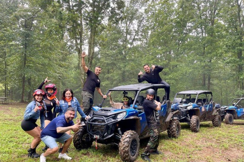 A group of people with ATVs in a forested area. 1