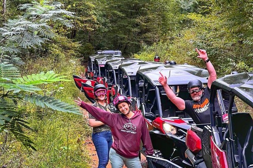 A group of people in a forested area with off-road vehicles. 2