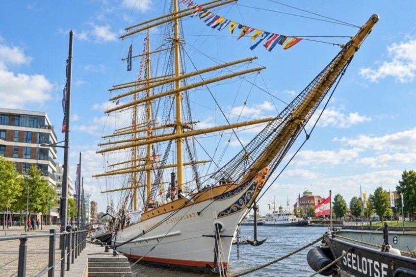 A tall ship docked at a harbor with a cityscape in the background. 5