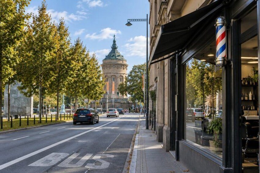 A street with a bus lane, trees, a building with a barber shop, and a tower in the background. 5