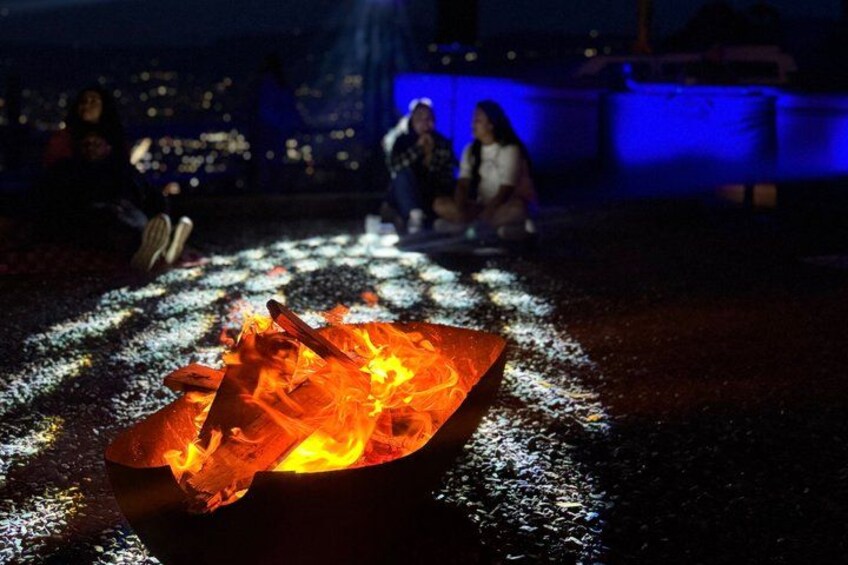 A campfire with flames and smoke, surrounded by a dark, reflective ground. 5