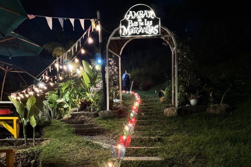A nighttime garden with a sign reading 'AMBAR Botes las Maravillas,' string lights, and a pathway. 3