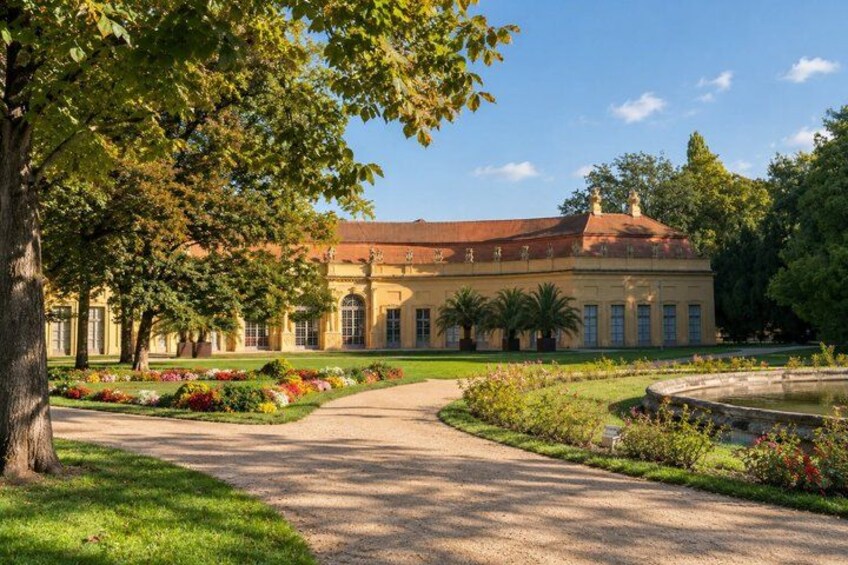 A classical building with a red roof, surrounded by a well-manicured garden with a variety of colorful flowers and a central fountain. 3