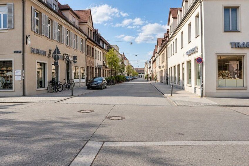 A quiet street with buildings, a parked car, and a bicycle. 4