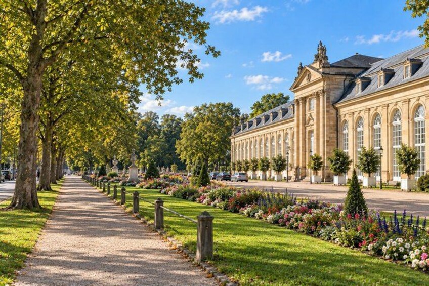 A tree-lined pathway leading to a classical building with a symmetrical facade and arched windows. 5