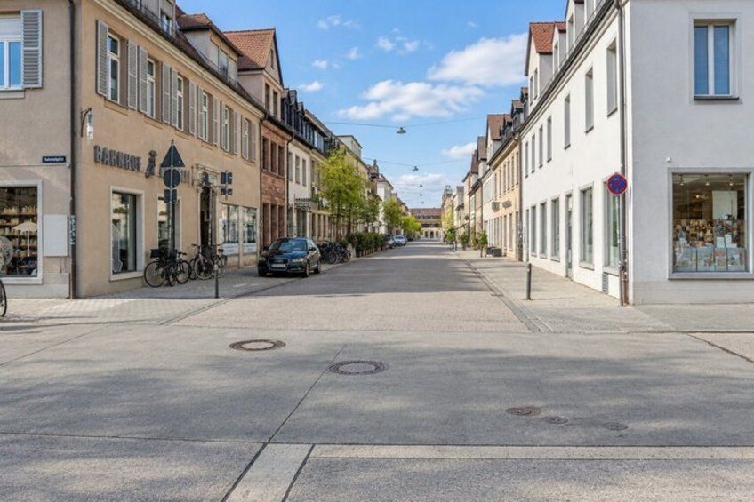 A quiet street with buildings on both sides, a parked car, and a bicycle. 4