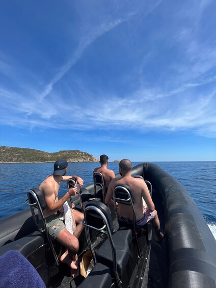 A group of people on an inflatable boat on a body of water with a clear sky and distant land. 1