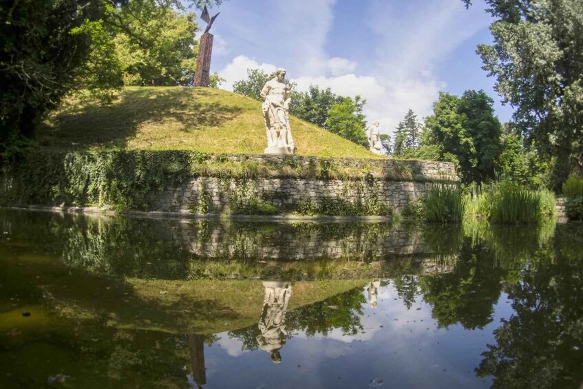 A statue on a grassy hill with a body of water in the foreground reflecting the statue. 4