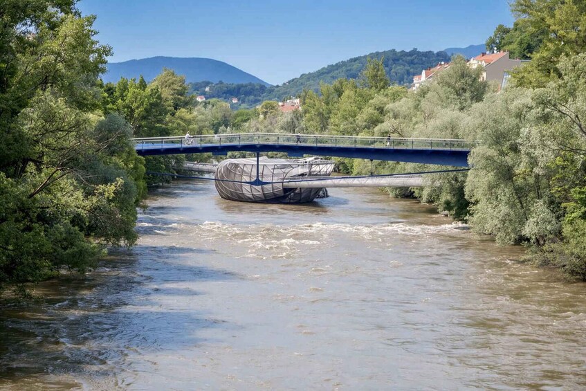 A river with a bridge, surrounded by trees and hills. 3