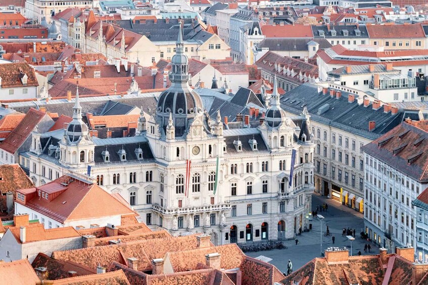 A historic building with a prominent dome and classical architecture, surrounded by other buildings with red-tiled roofs. 1