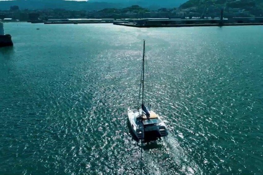 A sailboat on calm water with a bridge in the background. 1