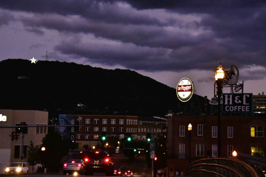 A street scene at night with a Dr Pepper sign, a H&C Coffee sign, and a star on a hill in the background. 3