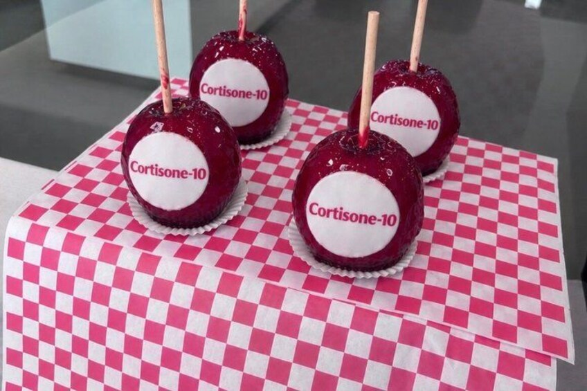 Four red candy apples with white labels on a checkered tablecloth. 1