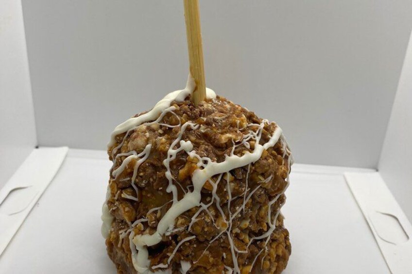 A caramel apple with white icing and a stick. 4