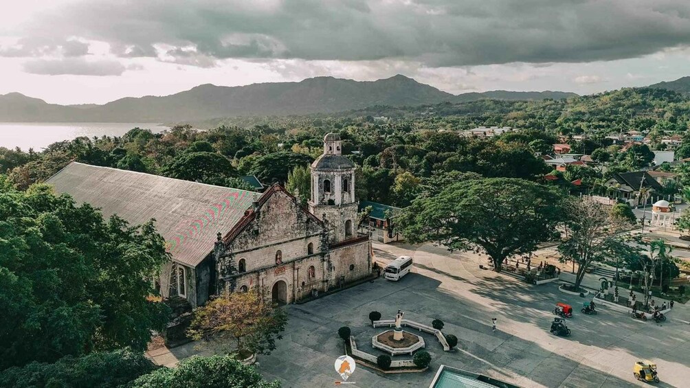 An old church with a bell tower, surrounded by lush greenery and a body of water. 3