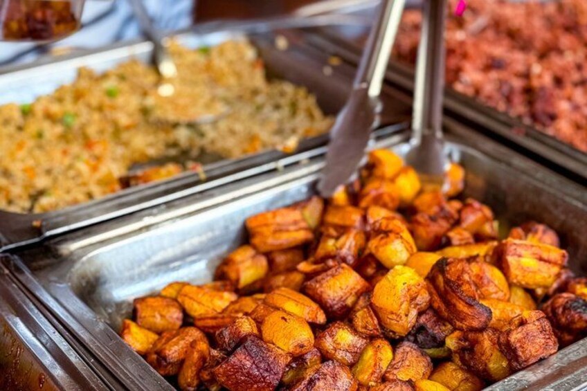 A buffet with various dishes including fried plantains and a rice dish. 4