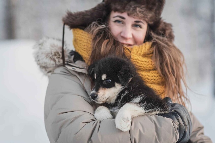 En person i en vinterjacka som håller i en hund. 1