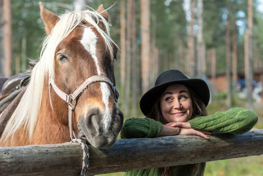 En person som lutar sig mot ett trästaket med en häst bredvid sig. 3