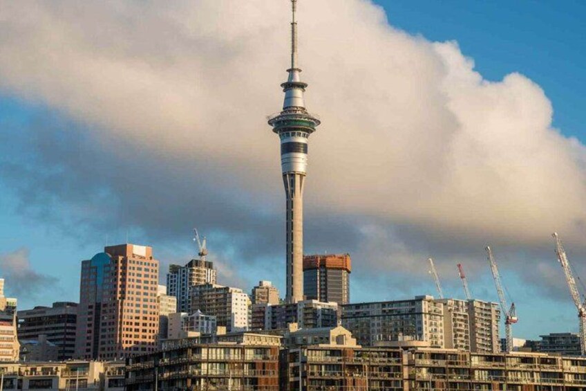 A city skyline with a prominent tower, several high-rise buildings, and construction cranes. 5