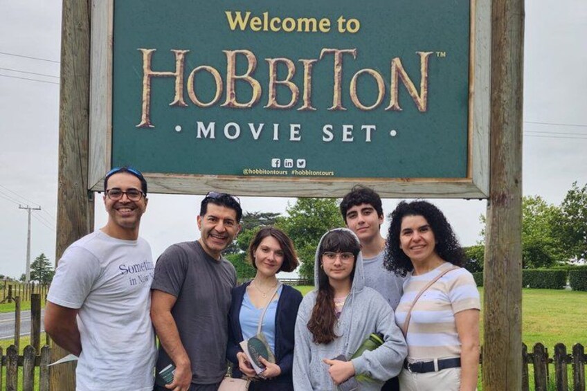 A group of people standing in front of a sign that reads 'Welcome to Hobbiton Movie Set.' 4